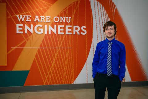 Michael standing in front of 'we are ONU engineers' wall sign