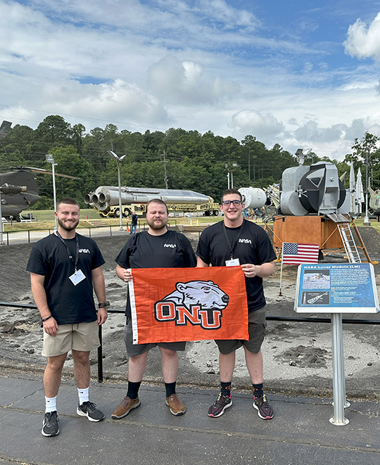 Photo of students by attraction holding ONU flag