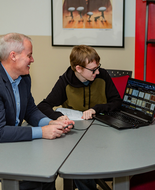 Photo of Art and Design class, ONU student and faculty sitting around a laptop