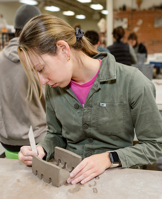 Photo of Art and Design class, ONU student working on her clay structure