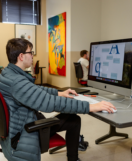 Photo of Art and Design class, ONU student sitting behind a desktop looking at the screen