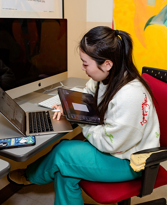 Photo of Art and Design class, ONU student holding an iPad while working on a laptop