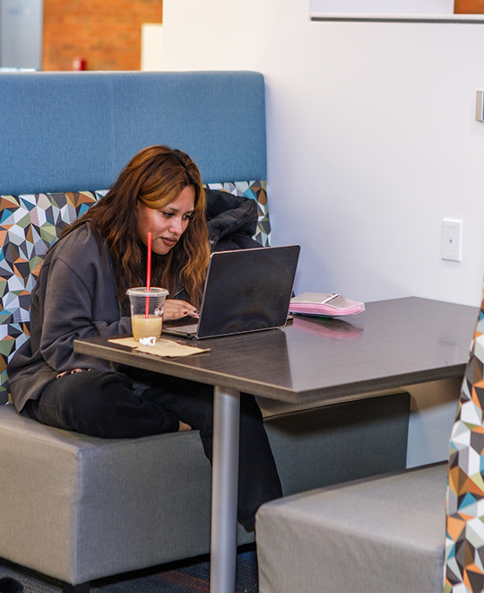 Photo of another ONU student sitting in a booth working on their laptop