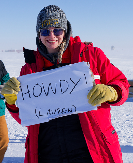 Photo of Lauren holding a sign that says Howdy! 