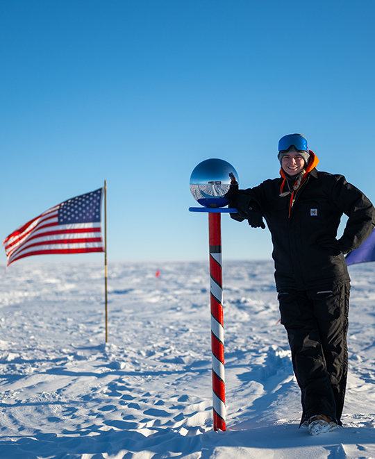 Photo of Lauren at the South Pole with a United States flag nearby