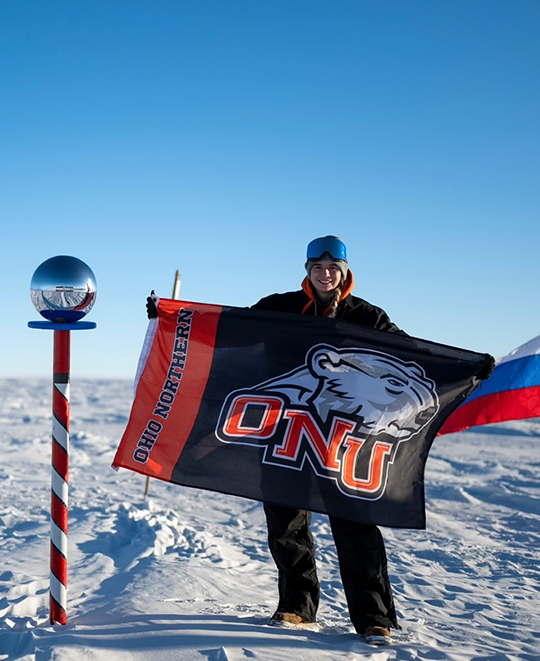 Photo of Lauren at the South Pole holding an ONU flag