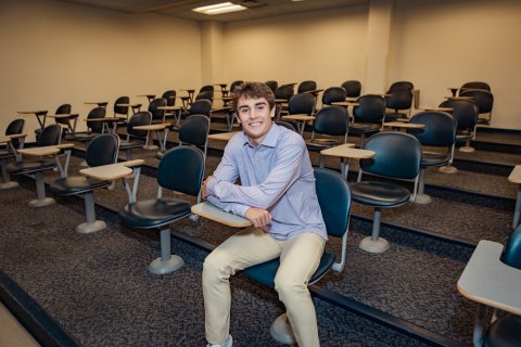 Photo of Colin sitting at a classroom desk