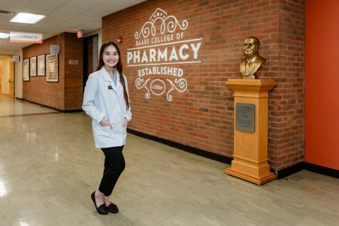 Photo of Giang in front of Pharmacy sign in the hallway