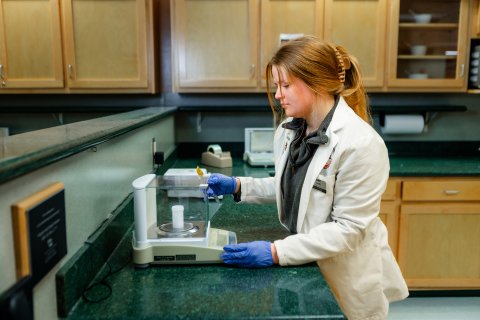 Photo of Abby looking into a microscope