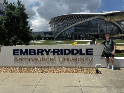 Photo of Caleb next to Embry Riddle Signage