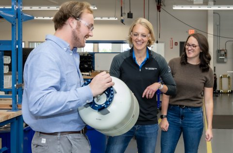 Jen with coworkers holding a tank of some sort