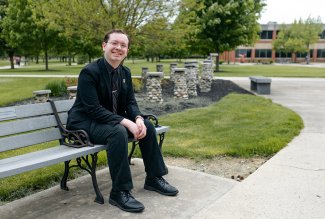 Photo of Spencer sitting on a bench on campus