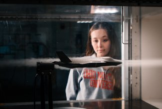 An Ohio Northern University engineering student observing a model airplane's functionality in a wind tunnel.